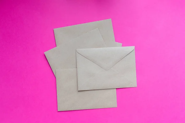 Крафт бумажные конверты на ярко-розовом фоне — стоковое фото