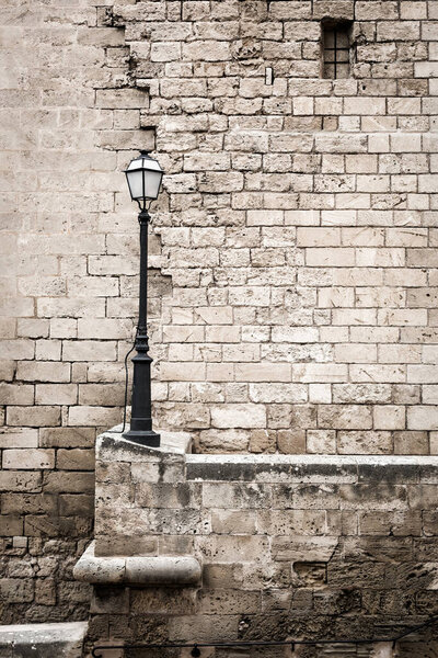 Beige contrast brick wall and lamppost. European old town view. Medieval stone wall. Abstract background.