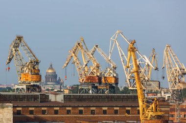 İskele vinçleri olan sanayi manzarası. Saint Petersburg limanı, Rusya. St. Isaac Katedrali 'nin arka planında bağlantı ekipmanları var.
