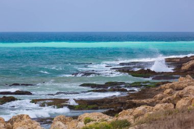Muhteşem turkuaz dalgalar ve beyaz köpük. Dalgalar Lübnan 'ın kayalık sahillerine çarpıyor. Mavi deniz suyu. Taş plajlı canlı bir deniz manzarası. Lübnan Akdeniz kıyı şeridi