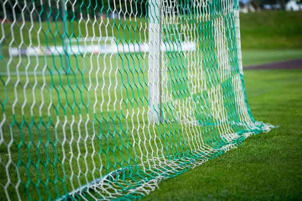 Football soccer goal. Post of football goal and white net in the foreground. Soccer stadium in the background. Summer sunny day