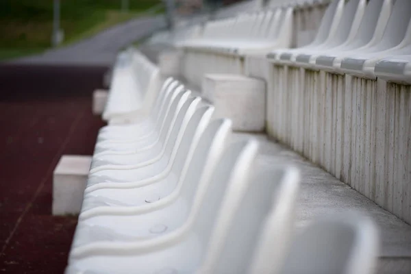 White seats in the stadium fans zone. Grandstand fans in a small sports stadium. Place for sporting events.