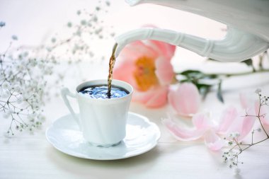 A cup of coffee and fresh flowers on a white table. clipart