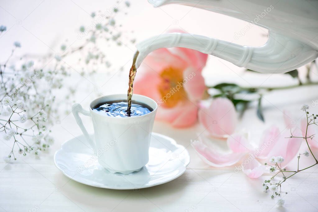A cup of coffee and fresh flowers on a white table.
