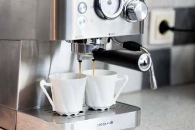 Bir kahve makinesi mutfakta espresso yapar. 2 fincan kahve.. 