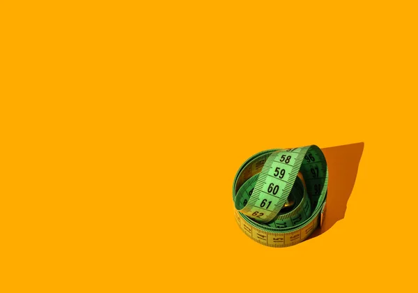 Зеленая измерительная лента на желтом фоне — стоковое фото