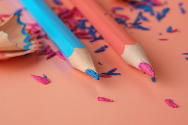 Mavi ve pembe kalemler ve pembe yüzeyde renkli ahşap ve grafit kalemler.