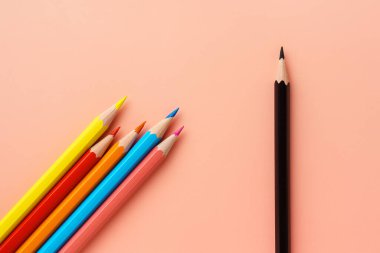 Renkli kalemler ve pembe arka planda tek siyah kalem.