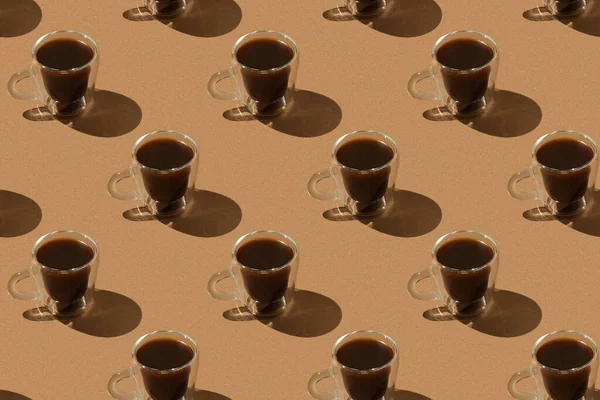 Patrón marrón: tazas de vidrio con café negro con sombra dura —  Fotos de Stock
