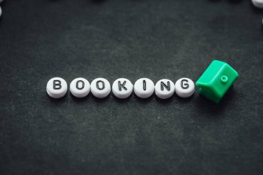 Word BOOKING on dark background made from. alphabet letters. Traveling concept