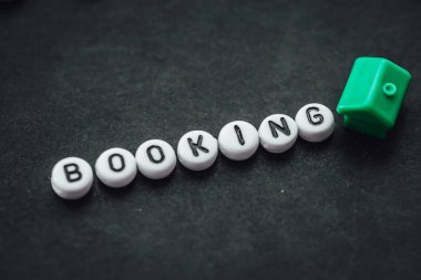 Word BOOKING on dark background made from. alphabet letters. Traveling concept