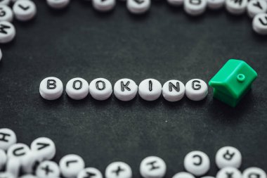 Word BOOKING on dark background made from. alphabet letters. Traveling concept