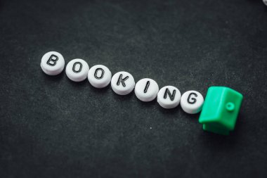 Word BOOKING on dark background made from. alphabet letters. Traveling concept