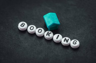 Word BOOKING on dark background made from. alphabet letters. Traveling concept