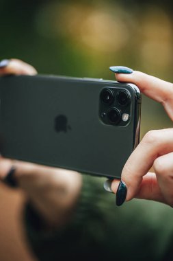 Riga, Latvia september 23, 2019 Woman using iphone 11 pro for photography, triple smartphone camera in close up