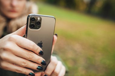 Riga, Latvia september 23, 2019 Woman using iphone 11 pro for photography, triple smartphone camera in close up