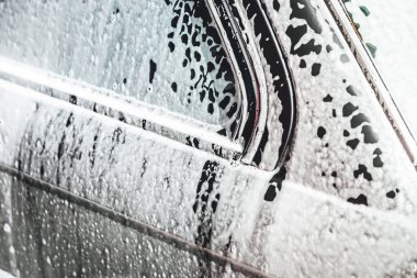 Temizlik sırasında köpükle kaplı araba, araba yıkama işlemi, çorbayla kaplı araba.