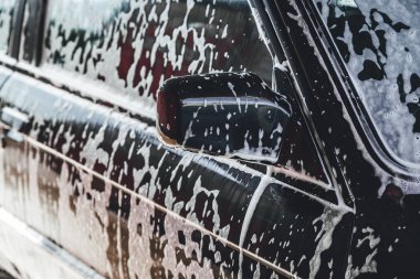 Temizlik sırasında köpükle kaplı araba, araba yıkama işlemi, çorbayla kaplı araba.