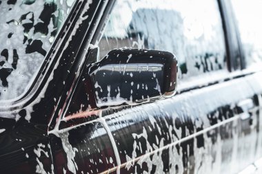 Temizlik sırasında köpükle kaplı araba, araba yıkama işlemi, çorbayla kaplı araba.