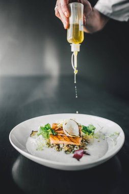 Restoran şefi karanlık masada balık yemeği hazırlıyor. Organik balık yemi.