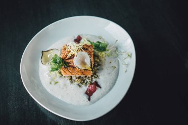 Restoran şefi karanlık masada balık yemeği hazırlıyor. Organik balık yemi.