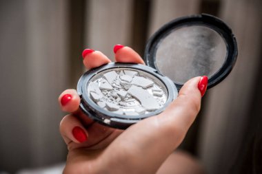 Kırık tutan kadın el görünümü kadar yakın toz içinde yuvarlak şekil konteyner, kırmızı renkli çivi Makyaj