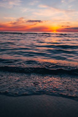 Deniz kenarında bir akşam, Baltık kıyılarında güzel bir gün batımı, küçük dalgalar üzerinde yakın bir manzara.