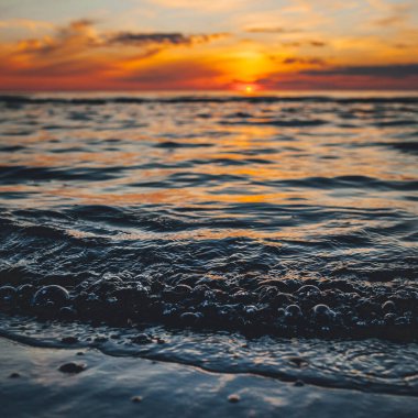 Deniz kenarında bir akşam, Baltık kıyılarında güzel bir gün batımı, küçük dalgalar üzerinde yakın bir manzara.