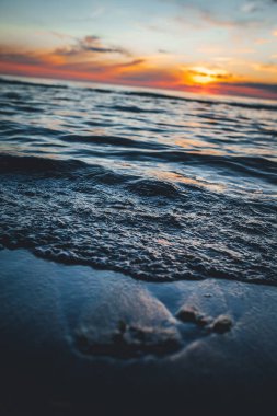 Deniz kenarında bir akşam, Baltık kıyılarında güzel bir gün batımı, küçük dalgalar üzerinde yakın bir manzara.