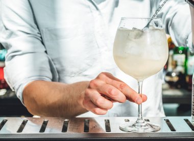 Barmen barda alkollü kokteyl hazırlıyor. 