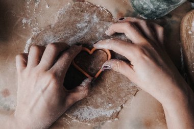 Kadın ve hamurun dokusu yakın plan. Kalp şeklinde zencefilli çörek. Sevgililer Günü için ev yapımı kurabiyeler.