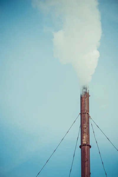 White industrial smoke from the chimney on a blue sky