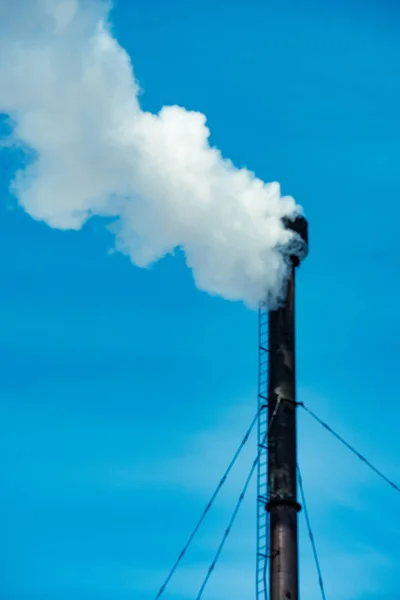 White industrial smoke from the chimney on a blue sky