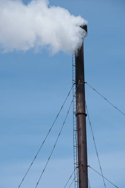 White industrial smoke from the chimney on a blue sky