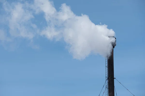 White industrial smoke from the chimney on a blue sky