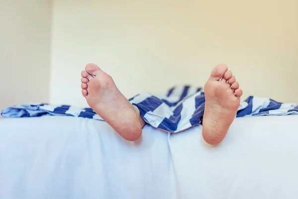Man sleeping in the bad, man feet in close up view