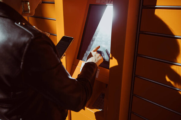 Young women using public parcel machine to sent mail