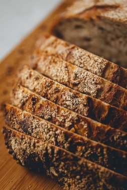 Yeni pişmiş ekşi ekmeğin, ahşap kesme tahtasının parlak arka planında yakın plan görüntüsü. 