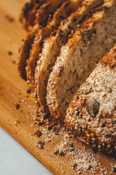 Close up view on freshly baked sourdough bread on wooden cutting board on bright backgrounda 