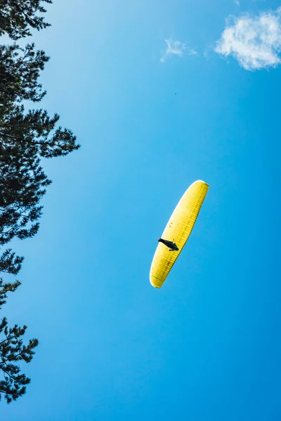 澄んだ青い空に対して明るい黄色のパラシュートを持つパラグライダー — ストック写真