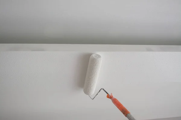 Pintura de um teto de gesso branco com rolo de pintura — Fotografia de Stock