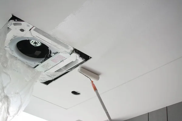 Boya rulo ile beyaz bir alçı sıva tavan boyama — Stok fotoğraf