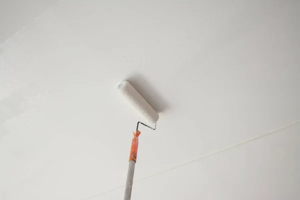 Painting a white gypsum plaster ceiling with paint roller — Stock Photo, Image
