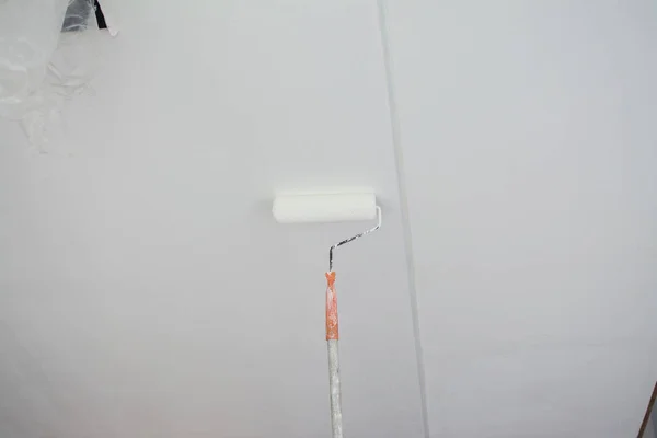 Pintar un techo de yeso blanco con rodillo de pintura —  Fotos de Stock