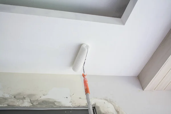 Покраска белого гипсового потолка с помощью ролика краски — стоковое фото