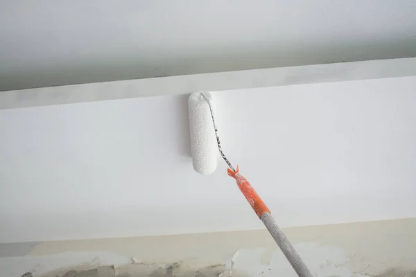 Pintura de um teto de gesso branco com rolo de pintura — Fotografia de Stock