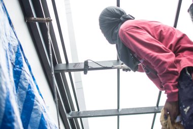 Çelik çatıyı boyayan işçiler, çatının altında..