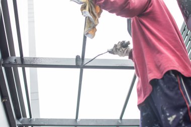 Çelik çatıyı boyayan işçiler, çatının altında..