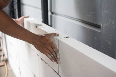 İnşaat ustası tuğla ustası mala ve çimento harcı ile tuğla işi yapıyor.