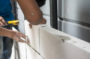 İnşaat ustası tuğla ustası mala ve çimento harcı ile tuğla işi yapıyor.